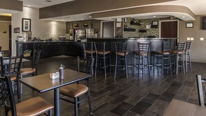 A modern restaurant with a bar area, dark wooden flooring, and contemporary furniture. - Red River Inn And Suites (Thackerville)