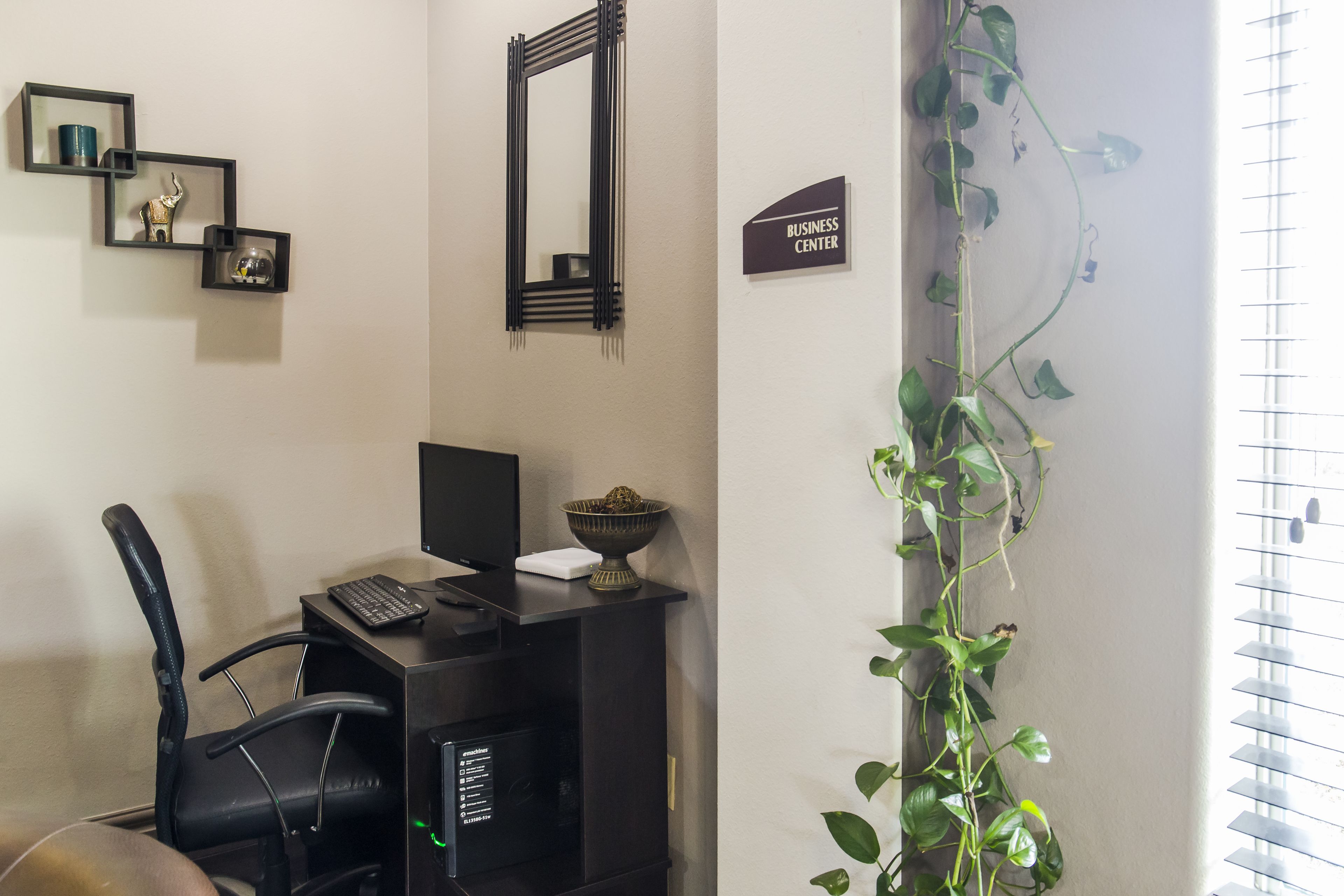 A workspace with a desk, chair, computer, and a potted plant.