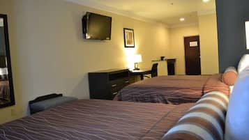 Habitación de hotel con dos camas, un escritorio, una silla, un televisor y una lámpara.