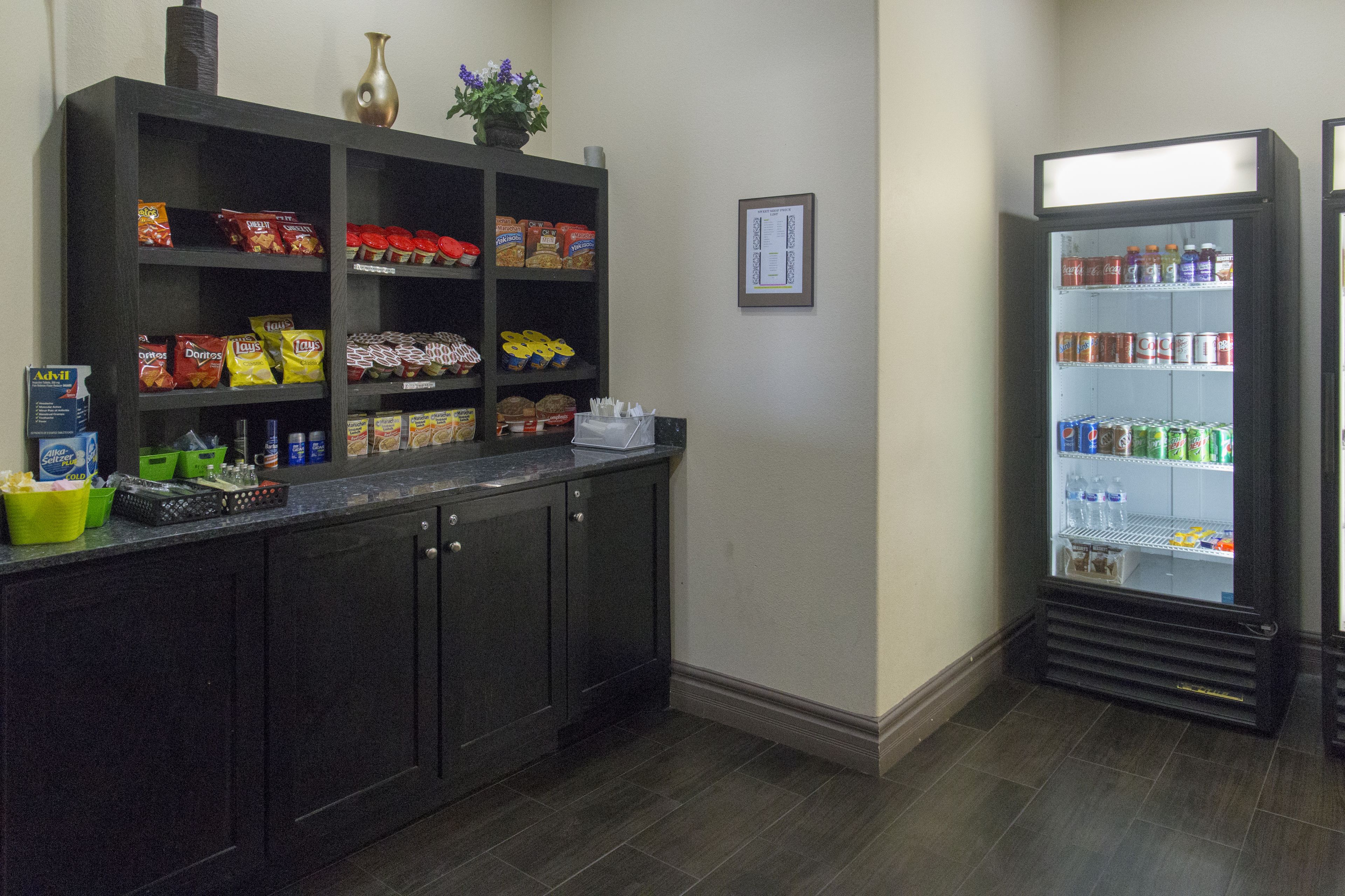 Una zona de cocina con un armario de madera oscura lleno de aperitivos y un refrigerador para bebidas.