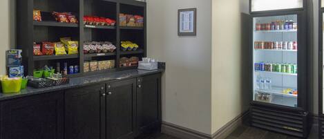 A kitchen area with a dark wood cabinet stocked with snacks and a beverage refrigerator.