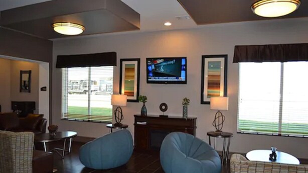 A modern living room with a fireplace, two bean bag chairs, a television, and large windows with blinds. - Red River Inn And Suites (Thackerville)