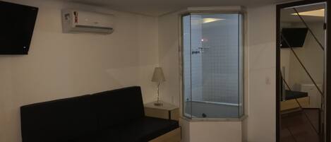 Een moderne hotelkamer met een bed, een klein nachtkastje, een lamp, een raam met uitzicht en een tv aan de muur.