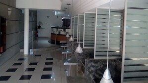 A modern lobby with a check-in counter, seating area, and a glass partition wall. - Estrela da Água Fria (São Paulo)