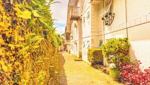 A narrow cobblestone alley flanked by buildings with balconies and potted plants. - VELINN Pousada Chateau do Luar Prime (Campos do Jordão)