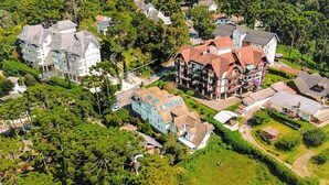 An aerial view of a residential area with multiple houses, including a large house with a red roof and a smaller house with a blue roof. - VELINN Pousada Chateau do Luar Prime (Campos do Jordão)