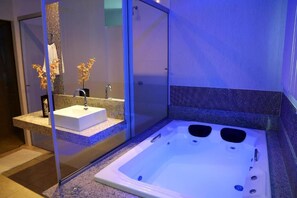 A modern bathroom with a glass-enclosed shower, a white sink, and a large bathtub. - Monte Castro Executive Hotel (Araguari)