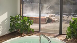 A hot tub with a wooden deck, surrounded by potted plants, and a view of a patio area with outdoor furniture. - WorldMark Steamboat Springs (Steamboat Springs)