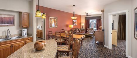 A hotel room with a kitchen, dining area, and a living room.
