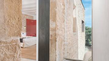 A modern interior with exposed stone walls, a bed, and a red accent wall.