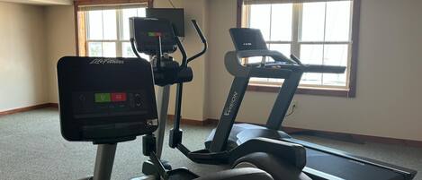 A gym with a treadmill and an elliptical machine.