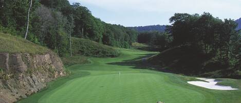 A golf course with a well-maintained green, sand bunkers, and a flagstick.