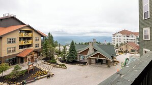 A building with a stone facade, a wooden balcony, and a view of mountains in the background. - Highland House (Snowshoe)