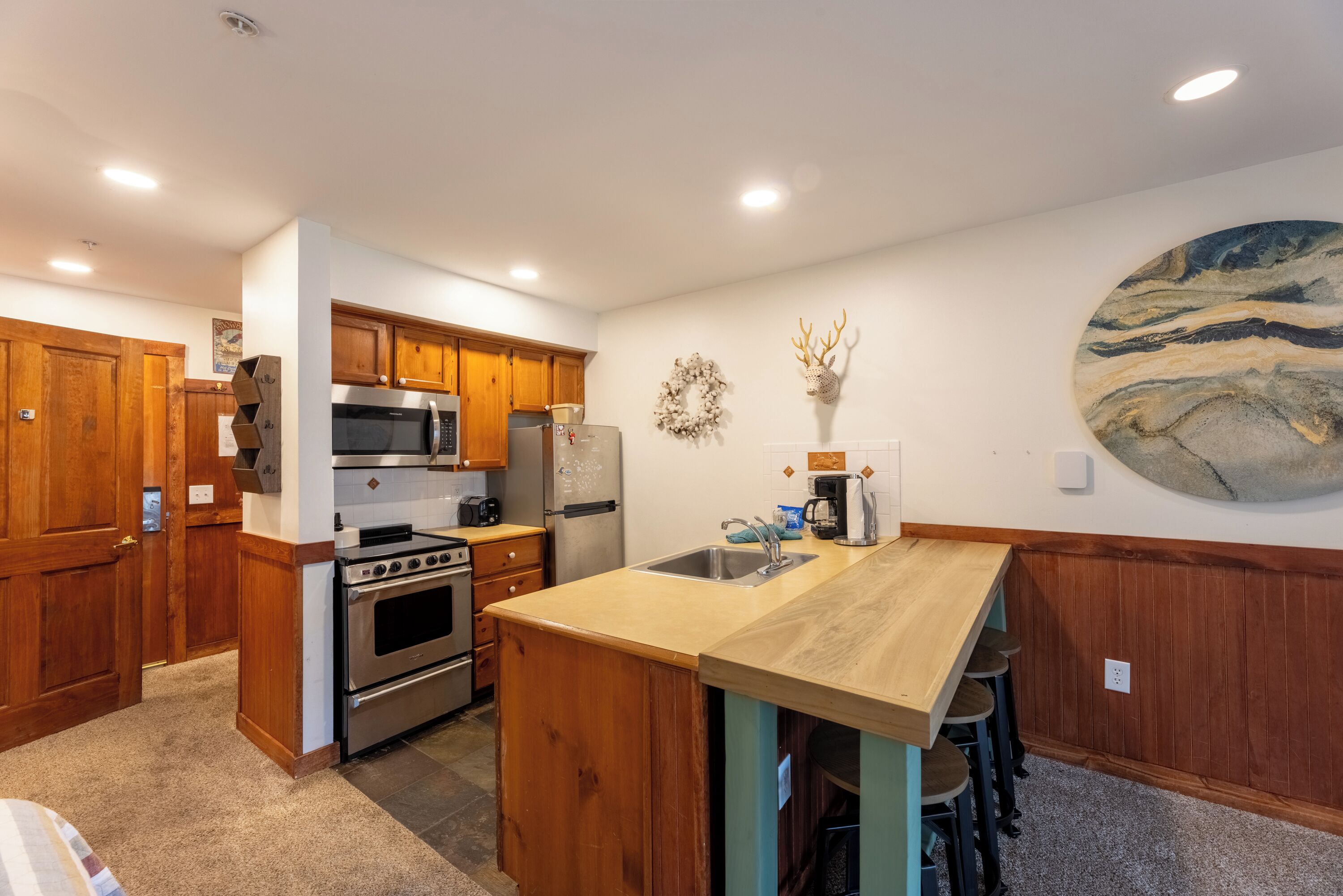 A kitchen with wooden cabinets, stainless steel appliances, a marble backsplash, and a central island with stools.