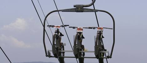 A cable car system with three gondolas suspended by cables, set against a mountainous backdrop.