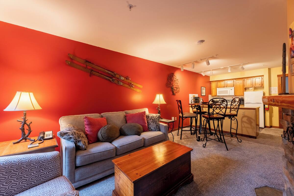 A living room with a sofa, coffee table, and a dining area with chairs and a table.