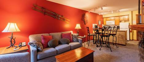 A living room with a sofa, coffee table, and a dining area with chairs and a table.