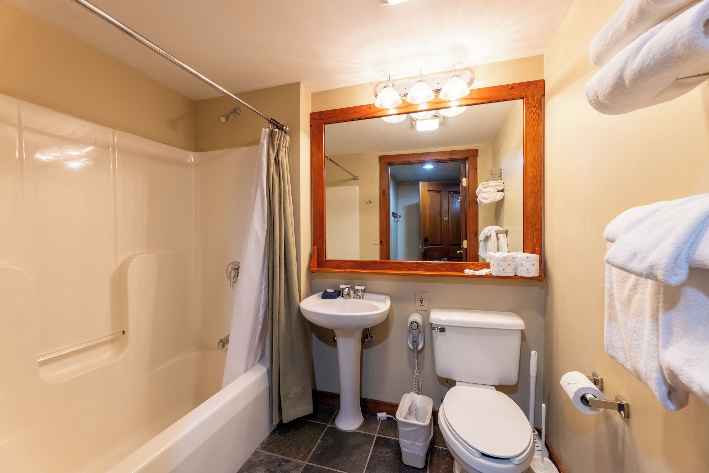 A bathroom with a bathtub, sink, toilet, and a mirror with lights.