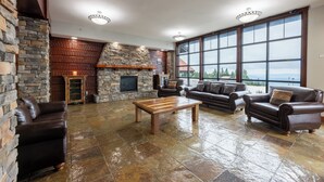 A spacious living area with stone walls, a fireplace, leather sofas, and large windows offering a view.