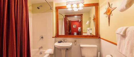A bathroom with a bathtub, sink, toilet, and a mirror above the sink.