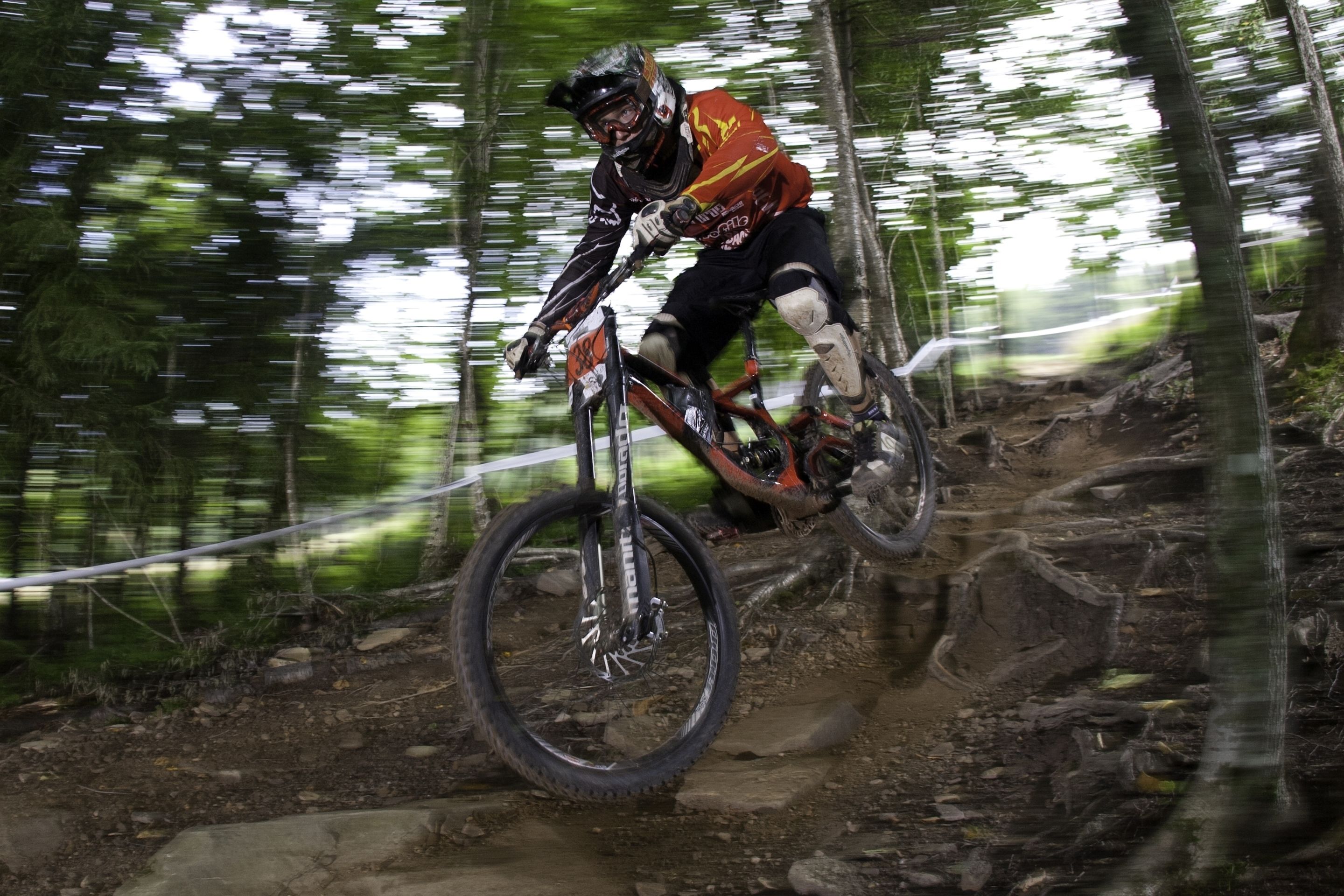 Un ciclista de montaña en un sendero de tierra rodeado de árboles.