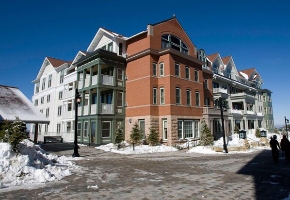 A multi-story building with a mix of brick and white facades, featuring large windows and a symmetrical design.