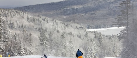 A snowy mountain landscape with two skiers.