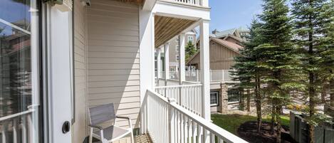 A wooden deck with a white railing, a bench, and a small table.