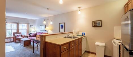 A kitchen with wooden cabinets, a stainless steel refrigerator, a dishwasher, and a window with a view.