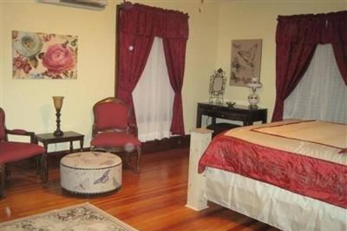 A bedroom with a bed, a chair, a table, and a rug.