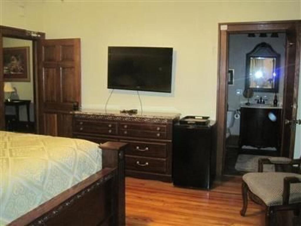 A bedroom with a bed, dresser, TV, and a small table.