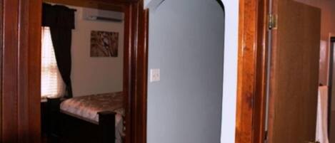 A room with a bed, a door, and a wall with a picture.