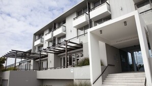 A modern hotel with a covered outdoor area, multiple balconies, and a staircase leading to the entrance. - Atlantic Beach Hotel (Cape Town)