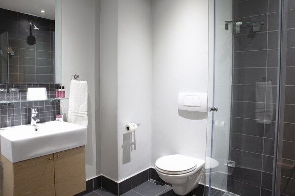 Un baño moderno con lavamanos, espejo y retrete blancos.
