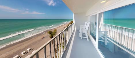 A balcony with a view of the beach and ocean.