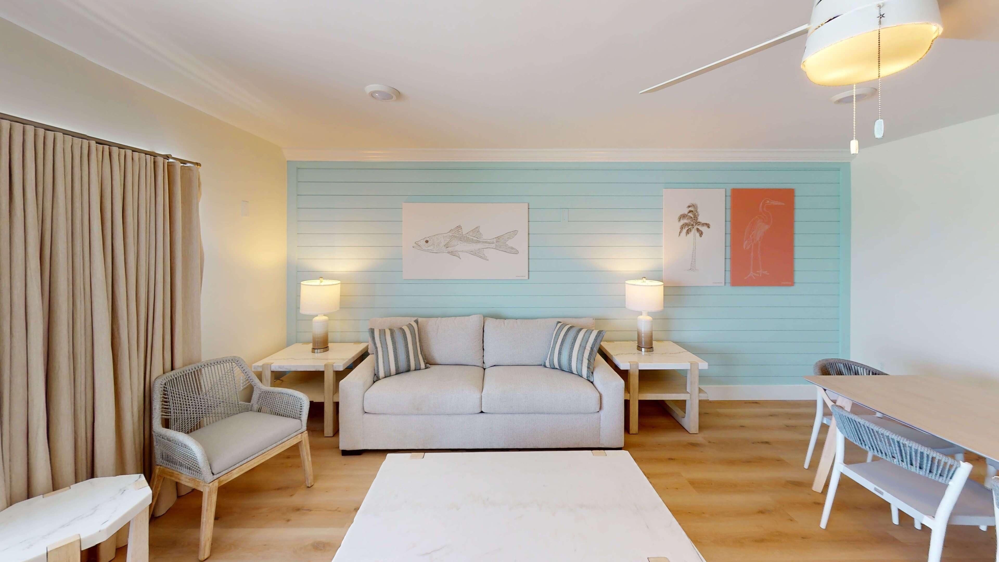 A living room with a sofa, two side tables with lamps, a white coffee table, and wicker chairs.