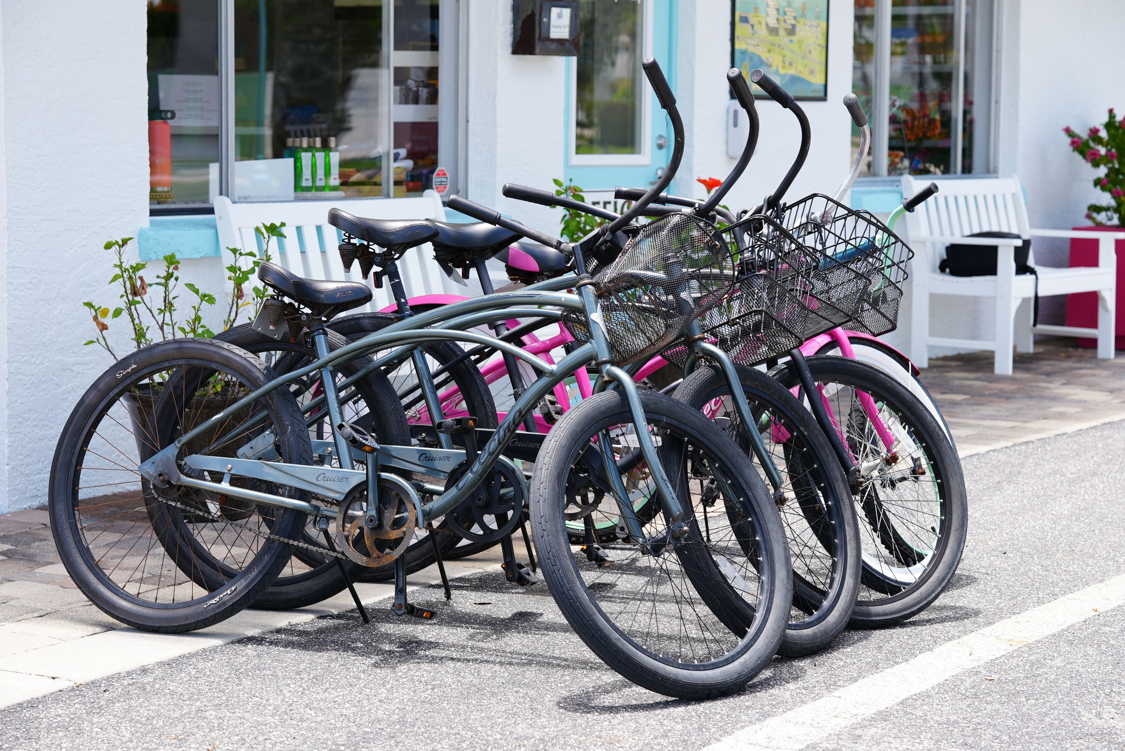A row of bicycles parked outside a building with a white exterior and a blue door.