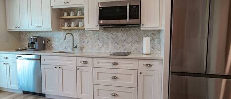 A kitchen with white cabinets, a stainless steel refrigerator, and a microwave.