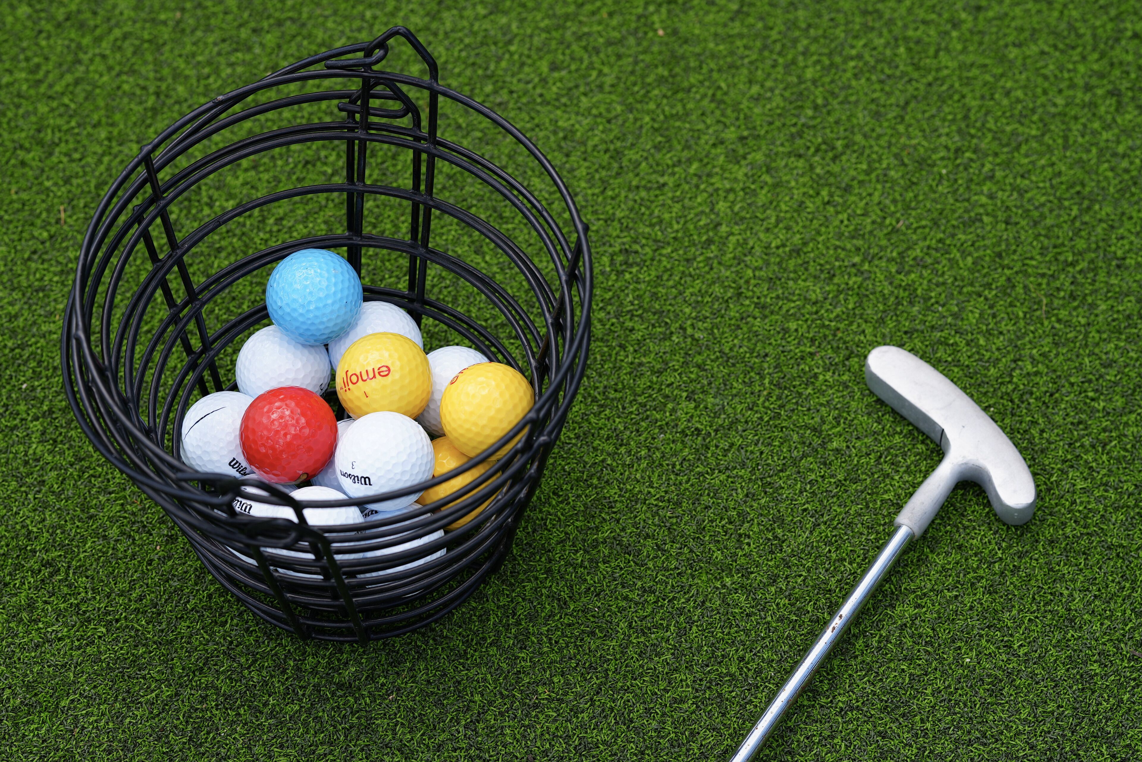 Ein Golfbag, gefüllt mit Golfbällen, auf künstlichem Rasen.