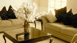 A living room with a sofa, armchairs, a coffee table, and a vase with flowers. - Scala Hotel (Lagos de Moreno)