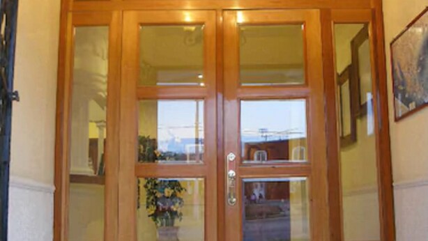 A wooden double door with glass panels and a chandelier above. - Scala Hotel (Lagos de Moreno)