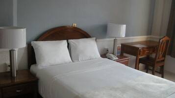 Ein Hotelzimmer mit Bett, Nachttischen, Schreibtisch und Stuhl.