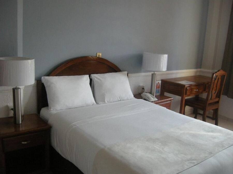 Ein Hotelzimmer mit Bett, Nachttischen, Schreibtisch und Stuhl.