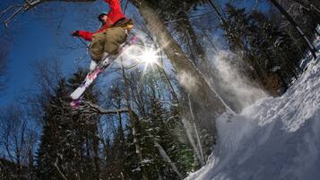 A snowboarder performing a jump in a snowy forest.