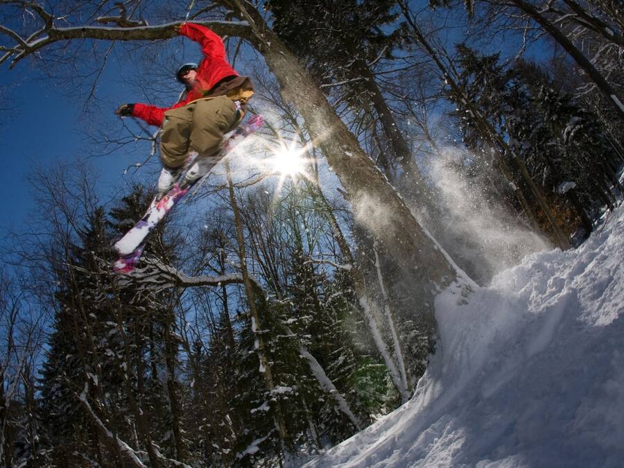 A snowboarder performing a jump in a snowy forest.