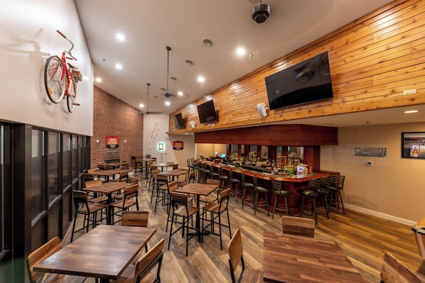Un restaurant doté d’un plancher en bois, d’un bar et d’un téléviseur fixé au mur.