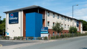 Ein Travelodge Hotel mit auffälliger blauer Fassade, einem Parkplatzschild und blauem Himmel.
