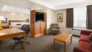 Habitación de hotel con cama, escritorio, silla, televisión y un sofá rojo.