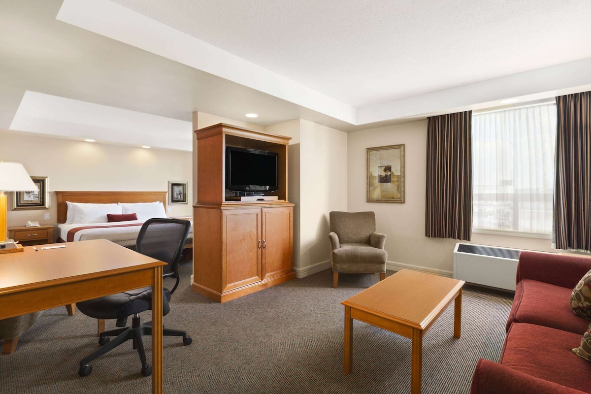 A hotel room with a bed, desk, chair, television, and a red sofa.