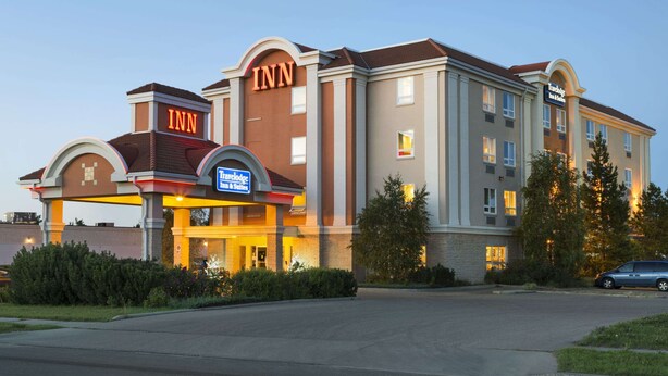 Un hotel de varios pisos con un cartel llamativo que dice 'INN', un cartel de Travelodge y un cartel de Tim Hortons.